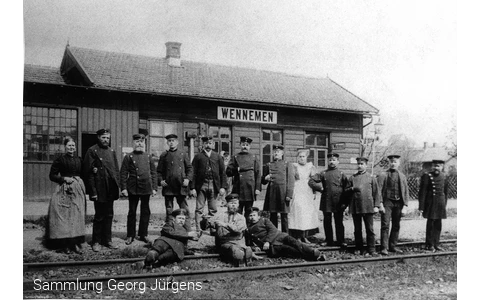 Das erste Bahnhofsgebäude von Wennemen um 1873. Der Zugverkehr scheint noch selten zu sein, sonst hätte man sich nicht zum Umtrunk und Foto im Gleis versammeln können